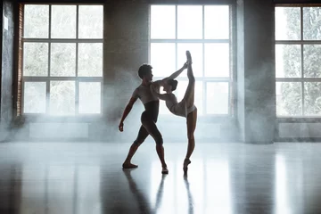 Fotobehang Dansschool Man and woman ballet dancers performing together against studio background