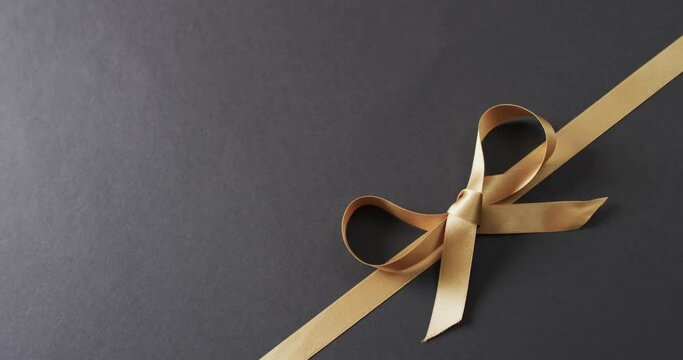 Video of gold gift ribbon and bow with copy space on black background