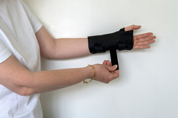 Female hands wearing bandage for carpal tunnel syndrome on the white wall background 