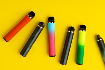 Colorful disposable electronic cigarettes on yellow background