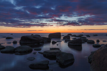 Late red sunset view of rocky sea shore, damatic light, long exposure