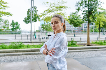 Portrait of teenage girl with crossed arms on street of city
