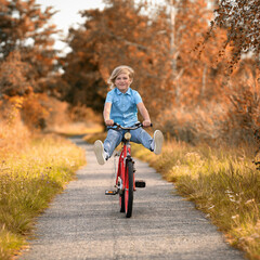 kleiner lachender Junge fährt Fahrrad im Herbst