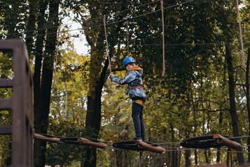 teenage boy in outdoor adventure park passing obstacle course. high rope park