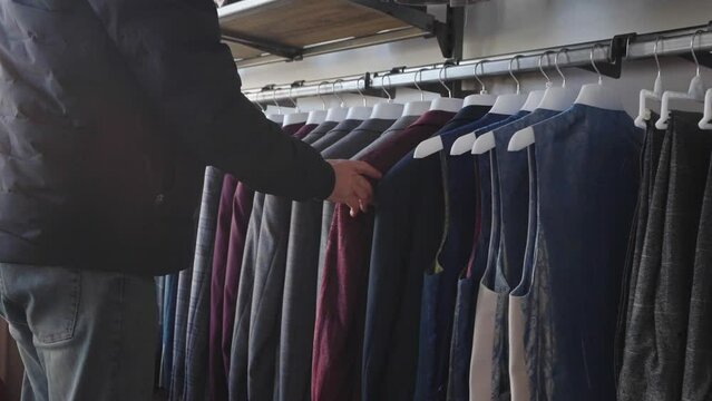 Man browsing in store for suit jacket to wear. Formal clothing for men