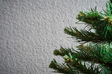 Christmas tree against a gray wall on right side