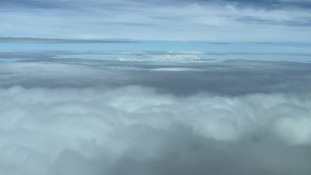 Flying across a clouded sky covered with layers and frayed white and grey clouds. A pilot&rsquo;s perspective.