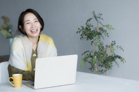 パソコンで仕事をする女性　カメラ目線で笑顔　webデザイナーや在宅などのお仕事のイメージ