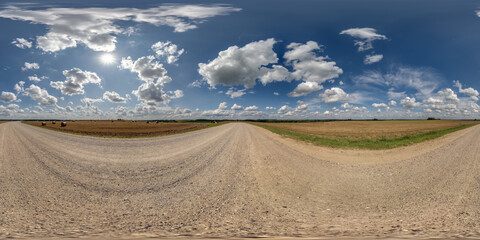 Obraz premium 360 hdri panorama on gravel road with marks from car or tractor tires with clouds on blue sky in equirectangular spherical seamless projection, skydome replacement in drone panoramas