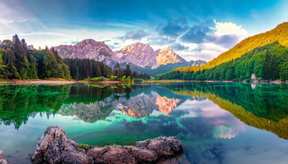 Calm morning view of Fusine lake. Colorful summer sunrise in Julian Alps with Mangart peak on background, Province of Udine, Italy, Europe. Beauty of nature concept background - Powered by Adobe