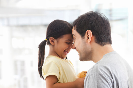 Smiling father and little daughter touching foreheads