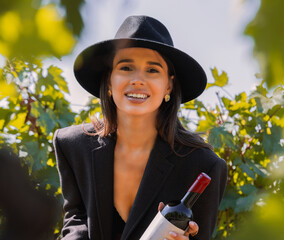 beautiful woman in vineyard with grape as eating,in mouth. attractive girl in masculine outfit and...