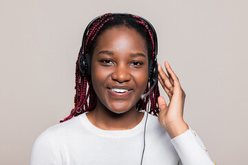 Cose up shot delighted happy African American dark skinned woman with braids operator in call center supportive customer concept receiving call from clients wearing wireless headset.