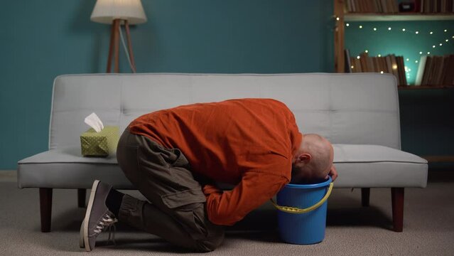 Food poisoning concept. Man suffering from nausea and vomiting on the couch at home