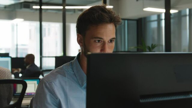 Young caucasian man in shirt using computer at desk in office
