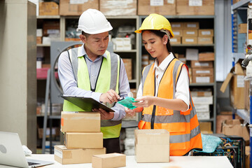 factory workers checking products from clipboard and cardboard box packaging in the warehouse storage