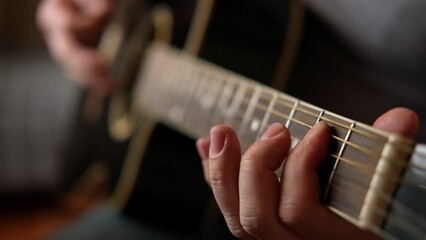 Playing the guitar. Strumming acoustic guitar. Musician plays music. Man fingers holding mediator. Man hand playing guitar neck in dark room. Unrecognizable person rehearsing, fretboard close-up	