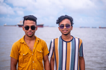 Portrait of south asian young boys with sunglasses on their eyes standing in front of a river 