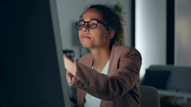 Black woman using desktop PC in dark office.