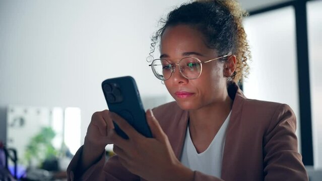 Black woman using smart phone in dark office.
