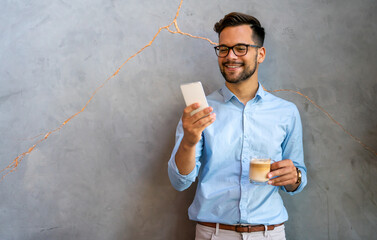 Handsome businessman checking emails on the phone in modern office in coffee break