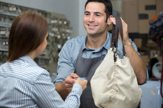 woman with tablet talking to shoemaker in workshop