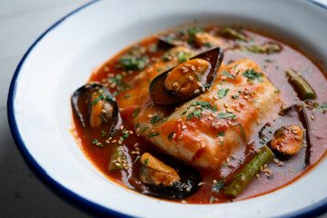 Hake with tomato sauce and mussels. Traditional recipe from northern Spain.