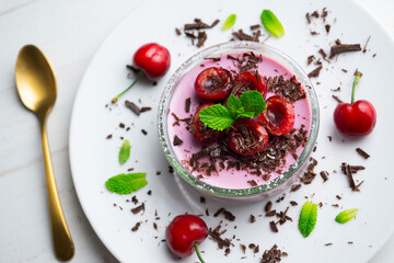 Cherry panna cotta served in a glass with fresh fruit and grated chocolate. - obrazy, fototapety, plakaty