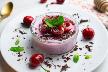 Cherry panna cotta served in a glass with fresh fruit and grated chocolate.