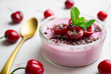 Cherry panna cotta served in a glass with fresh fruit and grated chocolate.