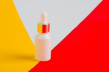 Cosmetic product in tube, bottle, lotion or serum on yellow and red and white background.