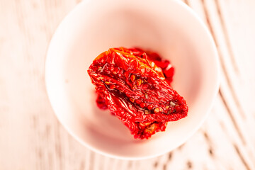 Sun-dried tomatoes in a plate on a cutting board