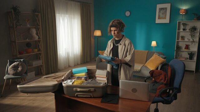 Shot Of A Teenager, Teen, Young Man Packing His Belongings, Clothes In A Suitcase On A Table. He Is Moving Out Or Going On A Vacation, Holiday.