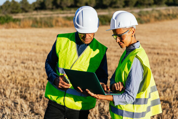 Engineers inspecting windmill operation with laptop software.