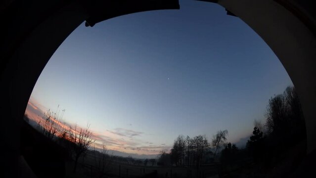 Morning window view with sky with moon and colorful sunrise, moving clouds during dawn and horizon with trees and car traffic on two-lane road - timelapse, panorama 204.