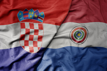 big waving national colorful flag of croatia and national flag of paraguay .