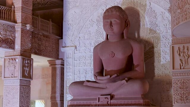 isolated red stone jain god holy statue in meditation from different angle video is taken at Shri Digamber Jain Gyanoday Tirth Kshetra, Nareli Jain Mandir, Ajmer, Rajasthan, India.