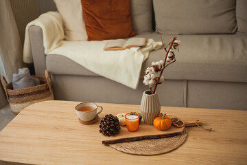 Autumn decor. Hot drink. Mug of tea, book, pumpkin, candle on a wooden coffee table. Autumn.