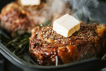  two juicy steaks are grilled, butter is spreading on top of the steaks