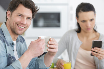 smiling man with angry woman on cell phone