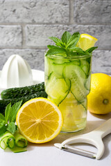 Healthy eating concept, fitness, detox drink. A glass of refreshing water with cucumber, lemon and mint, the process of preparing the drink.