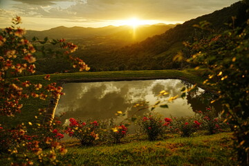 amanecer desde la montaña con un estanque y flores, paisaje embaucador 