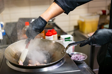 Professional chef cooking chicken curry food in wok pan on kitchen