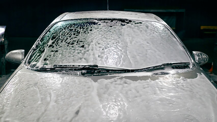 Car in foam. Car getting a wash with soap, car washing. Car closeup