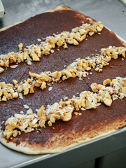 Filling on a layer of raw cinnamon dough. Making Cinnamon Roll