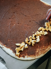 Filling on a layer of raw cinnamon dough. Making Cinnamon Roll