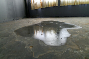 Close-up of spilled water leak on the floor of building. Wet floor from rainy splash or pipelines...