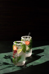 Two servings of a cooling cocktail with mint, lime and berries