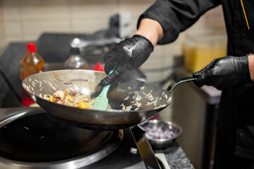 Chef cooking stir fry rice and chicken in wok pan at restaurant kitchen.