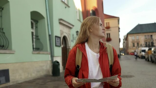 Real view of lost traveller woman walking on old Market Square in Krakow holding tourist map. Travel and active lifestyle concept. High quality FullHD footage